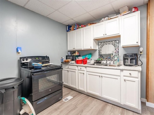 2517 Faraon St, Saint Joseph, MO 64501 - kitchen with black range with electric cooktop, a sink, a paneled ceiling, light countertops, and light wood-type flooring