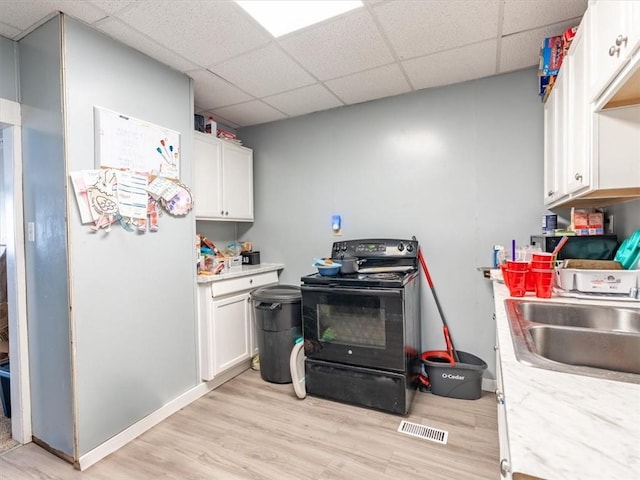 2517 Faraon St, Saint Joseph, MO 64501 - kitchen with black electric range oven, a drop ceiling, light wood-style flooring, and light countertops