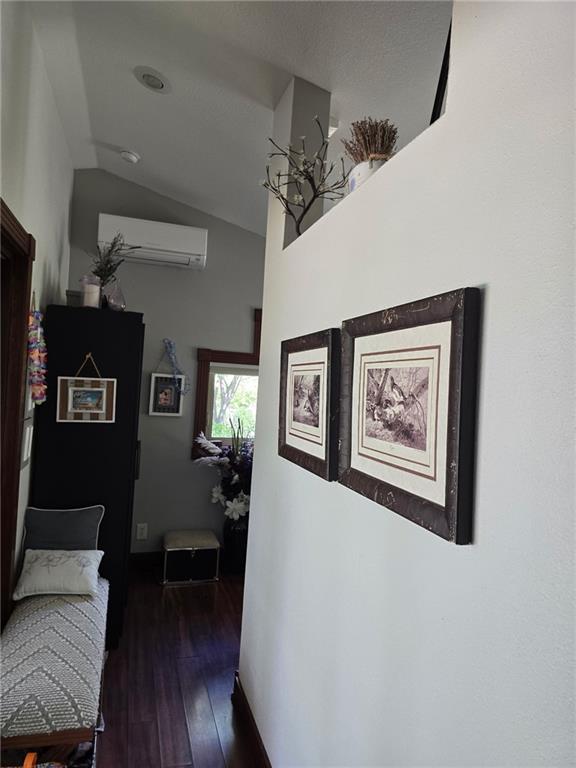 8050 SE Benner Lake Rd, Dearborn, MO 64439 - corridor with dark wood finished floors, a wall mounted air conditioner, and lofted ceiling
