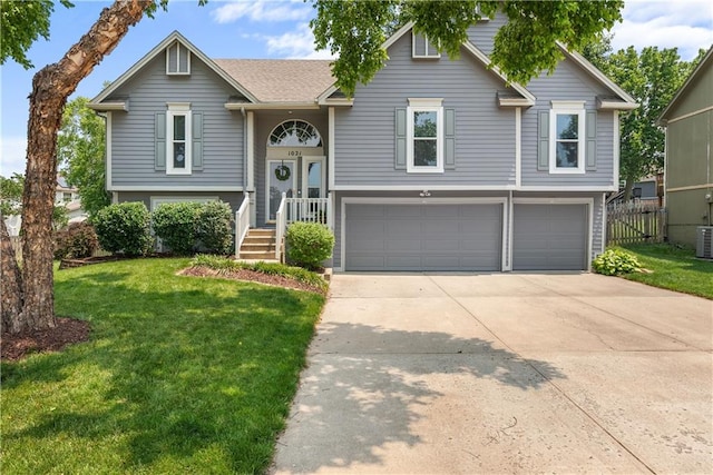 1021 NE Woodbury Ln, Lees Summit, MO 64086 - raised ranch featuring a garage, driveway, a front yard, and cooling unit