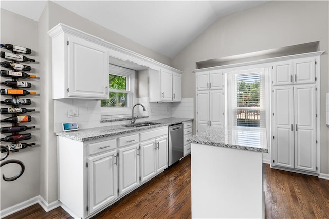 1021 NE Woodbury Ln, Lees Summit, MO 64086 - kitchen featuring stainless steel dishwasher, a sink, dark wood-style flooring, white cabinets, and vaulted ceiling