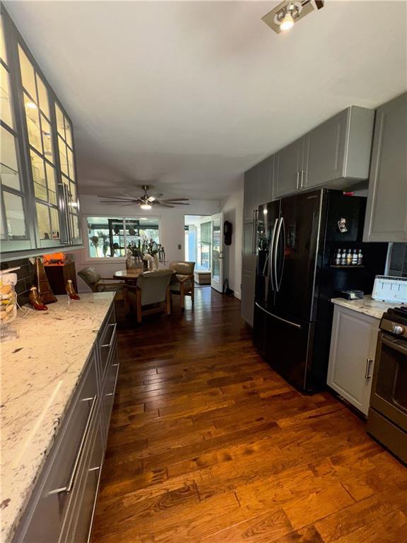 11500 Orchard Rd, Kansas City, MO 64134 - kitchen with stainless steel range, dark wood-style floors, gray cabinetry, and light stone counters