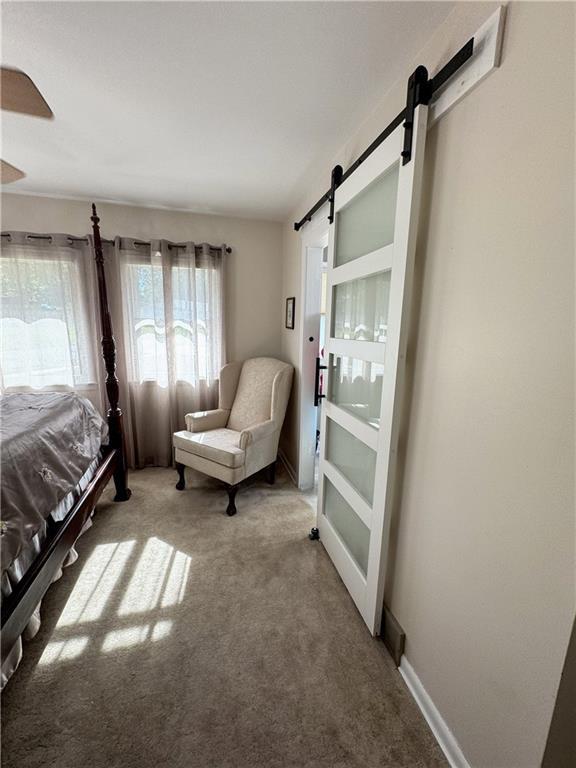 11500 Orchard Rd, Kansas City, MO 64134 - carpeted bedroom featuring a barn door and baseboards