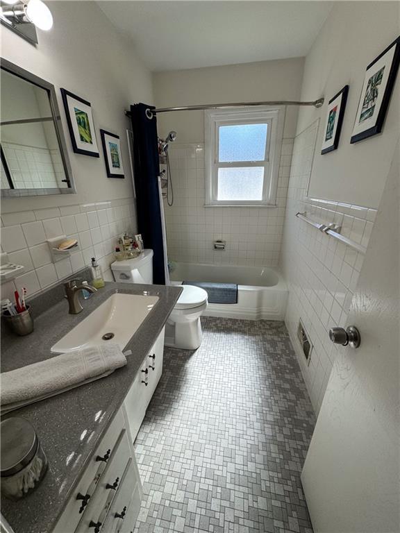 11500 Orchard Rd, Kansas City, MO 64134 - bathroom with tile walls, tiled shower / bath combo, toilet, vanity, and wainscoting