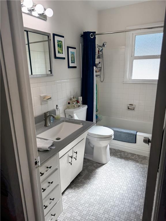 11500 Orchard Rd, Kansas City, MO 64134 - full bath with tile walls, vanity, toilet, shower / bath combo with shower curtain, and tile patterned floors