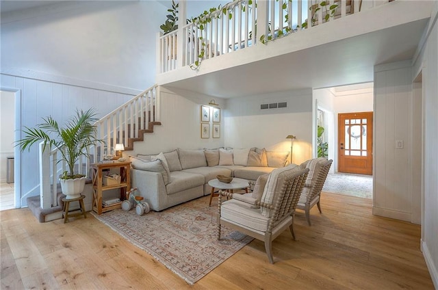 10236 Noland Rd, Lenexa, KS 66215 - living area featuring wood finished floors, stairway, a high ceiling, and a decorative wall