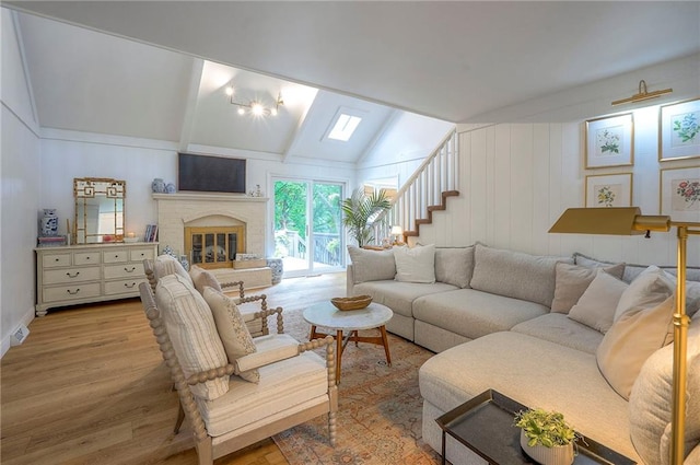 10236 Noland Rd, Lenexa, KS 66215 - living room with wood finished floors, lofted ceiling, a brick fireplace, and stairway