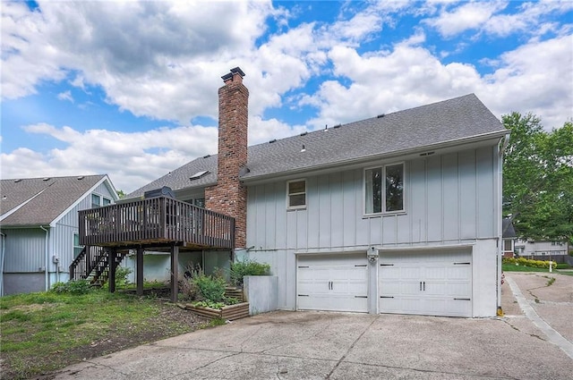 10236 Noland Rd, Lenexa, KS 66215 - rear view of property with stairway, an attached garage, a wooden deck, a chimney, and a shingled roof