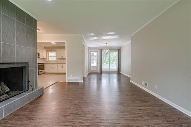 5112 Rock Creek Ln, Mission, KS 66205 - unfurnished living room with a chandelier, crown molding, dark wood-style flooring, a tile fireplace, and baseboards