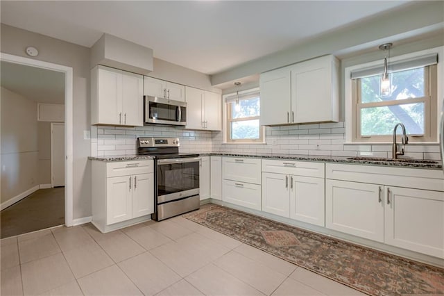 5112 Rock Creek Ln, Mission, KS 66205 - kitchen with appliances with stainless steel finishes, a sink, dark stone counters, decorative backsplash, and white cabinetry