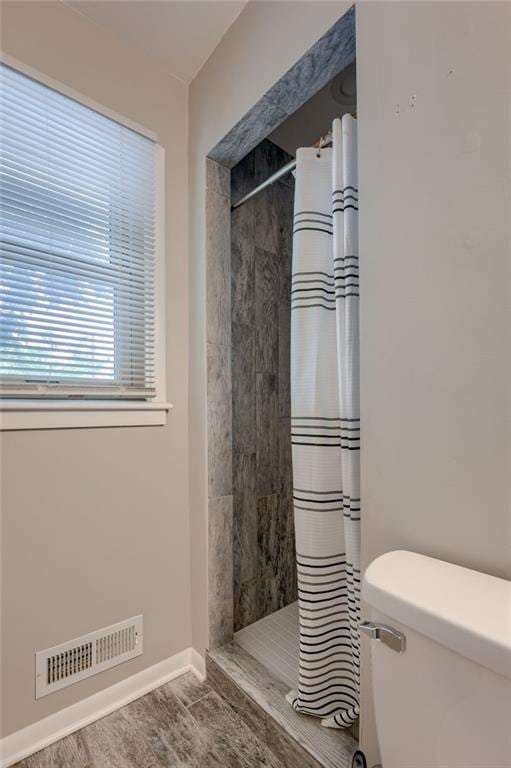 5112 Rock Creek Ln, Mission, KS 66205 - bathroom featuring a tile shower, toilet, and baseboards