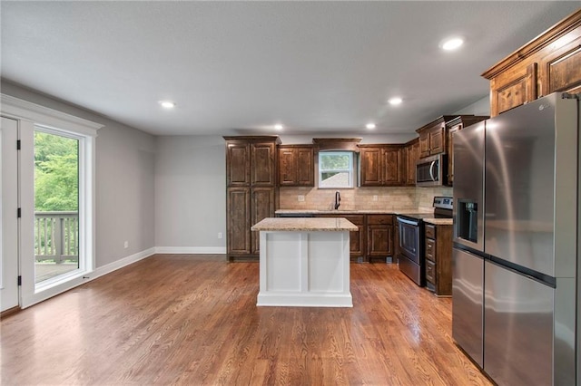 9 Platte Ridge Ct, Edgerton, MO 64444 - kitchen featuring appliances with stainless steel finishes, baseboards, wood finished floors, tasteful backsplash, and dark brown cabinetry