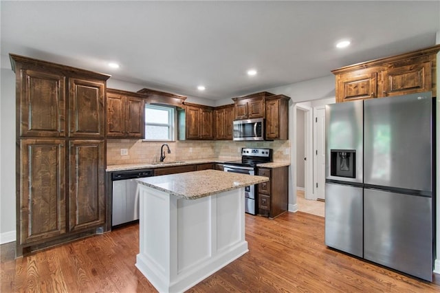9 Platte Ridge Ct, Edgerton, MO 64444 - kitchen with stainless steel appliances, a sink, backsplash, light stone counters, and wood finished floors