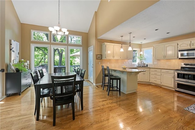 12577 S Alcan Cir, Olathe, KS 66062 - dining room with a chandelier, light wood-style flooring, and high vaulted ceiling
