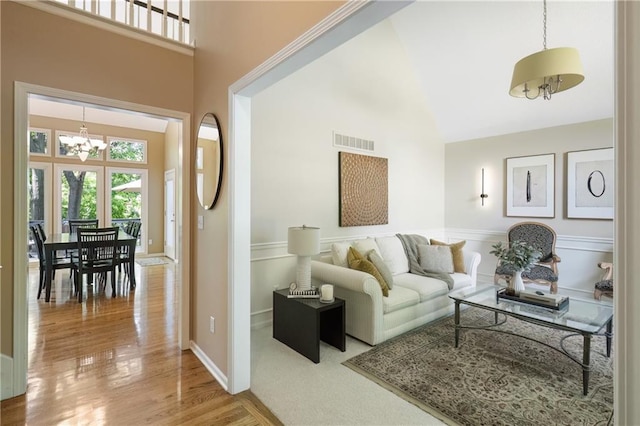12577 S Alcan Cir, Olathe, KS 66062 - living area with high vaulted ceiling, a chandelier, wood finished floors, and wainscoting