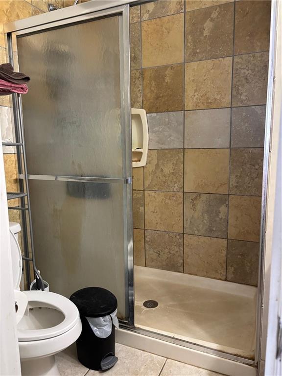 1024 Iowa St, Lawrence, KS 66044 - full bath with a shower stall, tile patterned flooring, and toilet