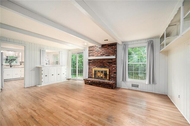 9601 W 97th St, Overland Park, KS 66212 - unfurnished living room featuring light wood finished floors, plenty of natural light, a sink, a brick fireplace, and beamed ceiling
