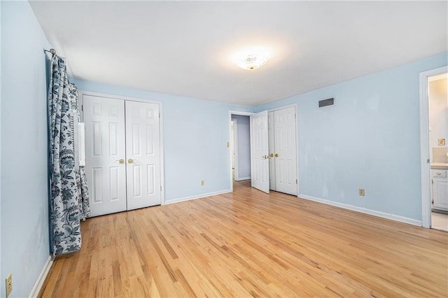 9601 W 97th St, Overland Park, KS 66212 - unfurnished bedroom with multiple closets, light wood-style flooring, baseboards, and ensuite bath