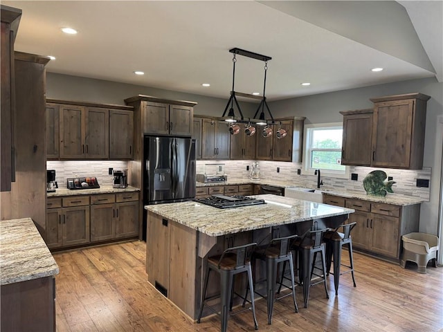 6601 Lakeside Cir, Odessa, MO 64076 - kitchen featuring black appliances, a sink, backsplash, a kitchen island, and light wood-style floors