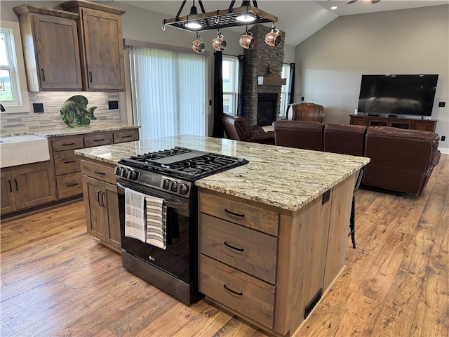 6601 Lakeside Cir, Odessa, MO 64076 - kitchen featuring range with gas stovetop, open floor plan, light wood-style floors, lofted ceiling, and a sink