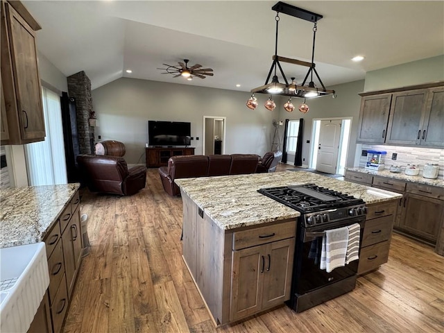 6601 Lakeside Cir, Odessa, MO 64076 - kitchen featuring black range with gas stovetop, a ceiling fan, light wood-style floors, lofted ceiling, and light stone counters