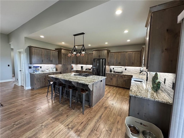 6601 Lakeside Cir, Odessa, MO 64076 - kitchen with black fridge with ice dispenser, a sink, a center island, a breakfast bar area, and tasteful backsplash