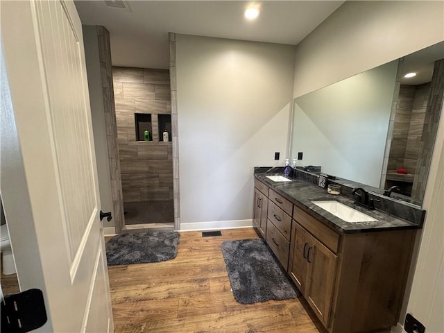 6601 Lakeside Cir, Odessa, MO 64076 - full bathroom with double vanity, wood finished floors, a tile shower, baseboards, and recessed lighting