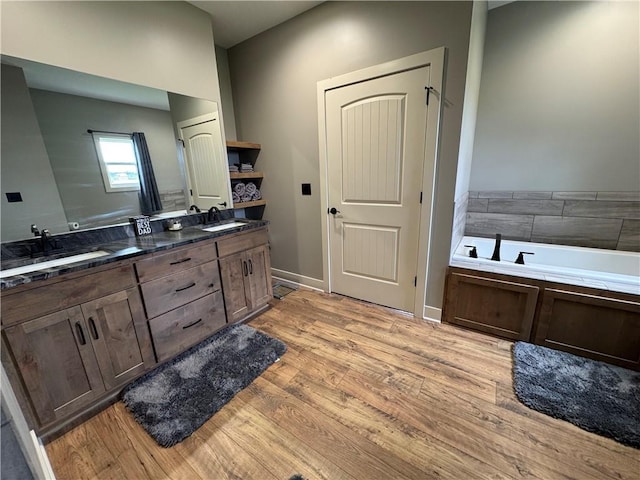 6601 Lakeside Cir, Odessa, MO 64076 - bathroom featuring double vanity, wood finished floors, a garden tub, and baseboards