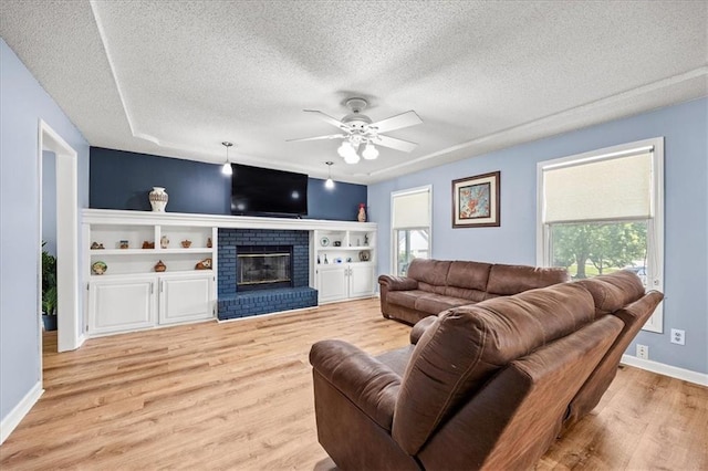 1305 N Hunter Dr, Olathe, KS 66061 - living area with a textured ceiling, a ceiling fan, light wood finished floors, and a brick fireplace