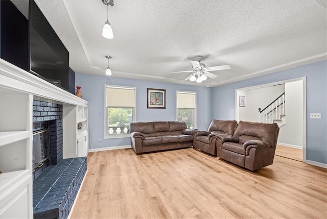 1305 N Hunter Dr, Olathe, KS 66061 - living room with a textured ceiling, a fireplace, wood finished floors, ceiling fan, and stairs