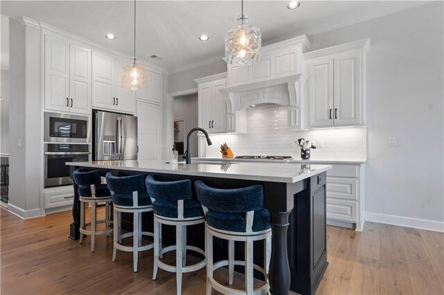 13389 W 147th Ter, Olathe, KS 66062 - kitchen featuring appliances with stainless steel finishes, decorative backsplash, a center island with sink, white cabinetry, and recessed lighting