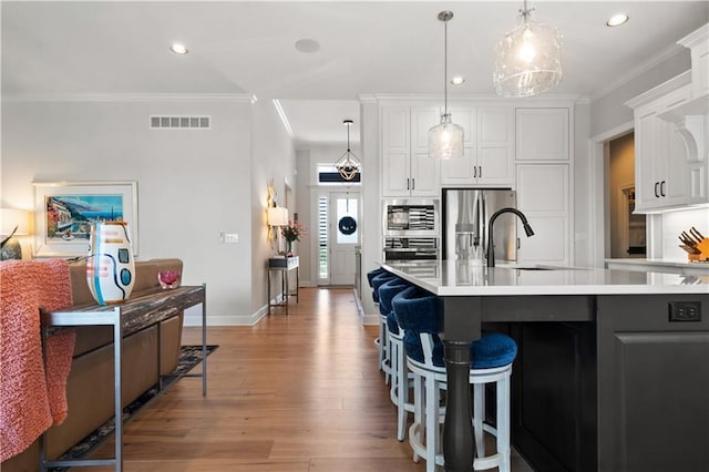 13389 W 147th Ter, Olathe, KS 66062 - kitchen featuring crown molding, light wood-style flooring, recessed lighting, appliances with stainless steel finishes, and white cabinetry