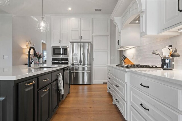 13389 W 147th Ter, Olathe, KS 66062 - kitchen with appliances with stainless steel finishes, white cabinetry, crown molding, light countertops, and decorative backsplash