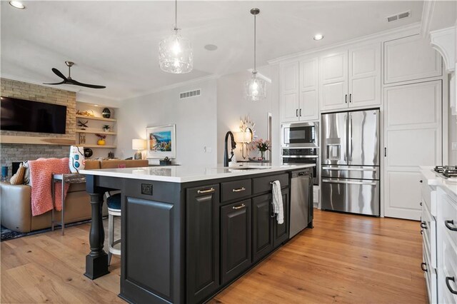13389 W 147th Ter, Olathe, KS 66062 - kitchen with stainless steel appliances, white cabinets, open floor plan, ornamental molding, and light countertops