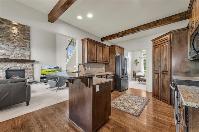 2301 NE 110th St, Kansas City, MO 64155 - kitchen featuring appliances with stainless steel finishes, beamed ceiling, a peninsula, dark wood-style flooring, and stone counters