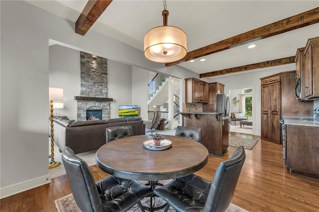 2301 NE 110th St, Kansas City, MO 64155 - dining space featuring beamed ceiling, stairway, a fireplace, wood finished floors, and recessed lighting