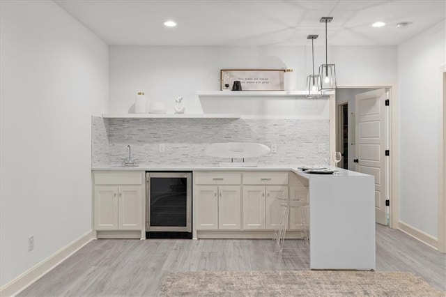 15945 W 165th St, Olathe, KS 66062 - indoor wet bar featuring wine cooler, light wood-style flooring, tasteful backsplash, baseboards, and recessed lighting