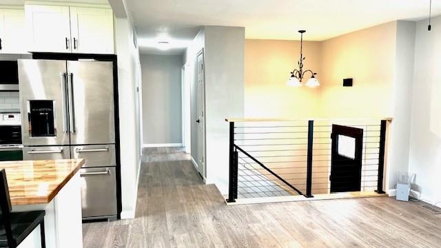 1636 S Poplar St, Ottawa, KS 66067 - kitchen with appliances with stainless steel finishes, butcher block counters, a chandelier, wood finished floors, and baseboards