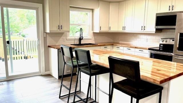 1636 S Poplar St, Ottawa, KS 66067 - kitchen with butcher block countertops, appliances with stainless steel finishes, a sink, and a kitchen breakfast bar