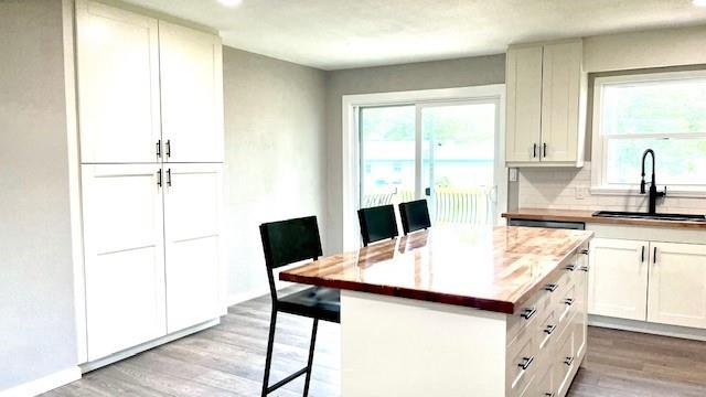 1636 S Poplar St, Ottawa, KS 66067 - kitchen with a sink, light wood finished floors, a breakfast bar area, tasteful backsplash, and light countertops