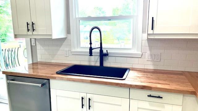 1636 S Poplar St, Ottawa, KS 66067 - kitchen featuring stainless steel dishwasher, a sink, wooden counters, backsplash, and white cabinetry