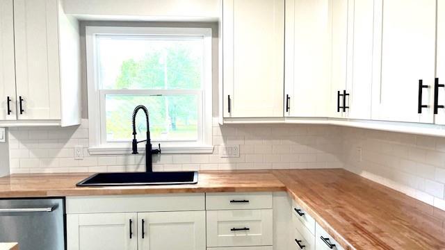 1636 S Poplar St, Ottawa, KS 66067 - kitchen with stainless steel dishwasher, a sink, and tasteful backsplash