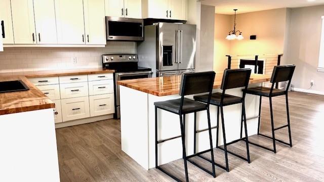 1636 S Poplar St, Ottawa, KS 66067 - kitchen with stainless steel appliances, wood counters, light wood-style floors, and a chandelier