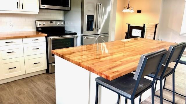 1636 S Poplar St, Ottawa, KS 66067 - kitchen featuring butcher block counters, appliances with stainless steel finishes, white cabinetry, and light wood-style flooring