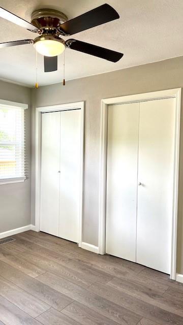 1636 S Poplar St, Ottawa, KS 66067 - unfurnished bedroom featuring two closets, light wood-type flooring, baseboards, and a ceiling fan