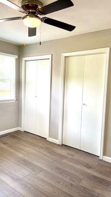 1636 S Poplar St, Ottawa, KS 66067 - unfurnished bedroom with multiple closets, wood finished floors, baseboards, and a ceiling fan