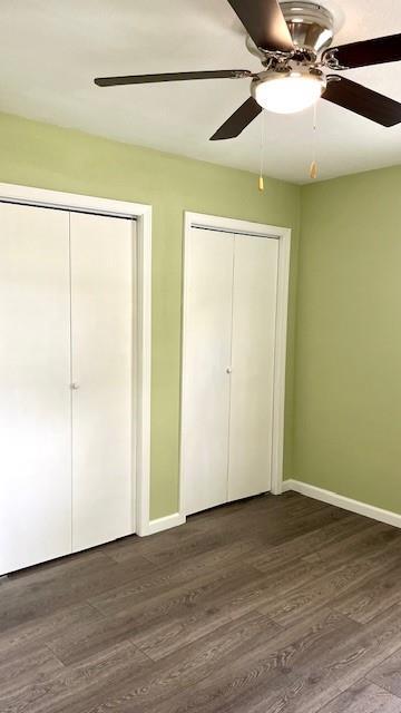 1636 S Poplar St, Ottawa, KS 66067 - unfurnished bedroom featuring multiple closets, dark wood-style flooring, baseboards, and ceiling fan