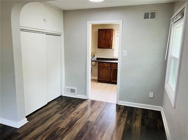 6823 S Benton Ave, Kansas City, MO 64132 - unfurnished bedroom featuring baseboards, wood finished floors, a closet, a textured wall, and ensuite bathroom
