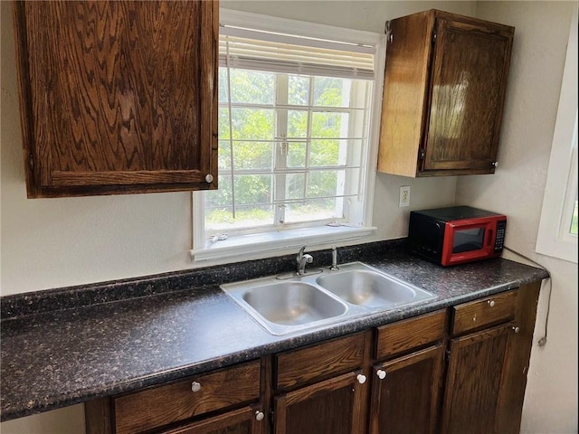 6823 S Benton Ave, Kansas City, MO 64132 - kitchen with a sink, dark countertops, plenty of natural light, and dark brown cabinets