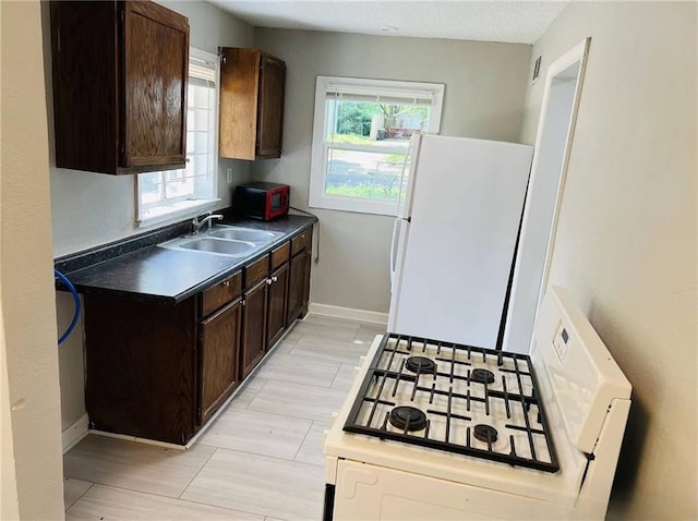 6823 S Benton Ave, Kansas City, MO 64132 - kitchen featuring white appliances, a sink, dark brown cabinets, dark countertops, and baseboards